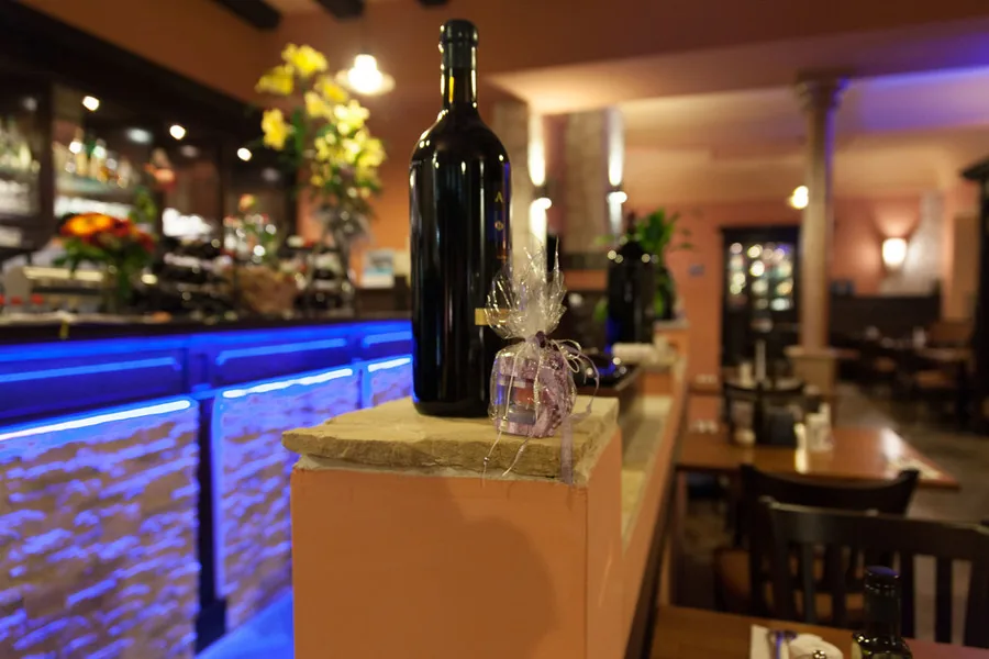 Theke mit großer Weinflasche und gelben Blumen